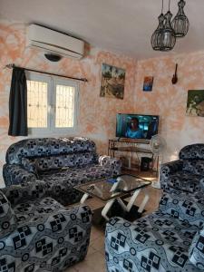 a living room with couches and a flat screen tv at Chez Andre in Ngaparou