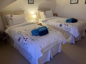 two beds with white sheets and blue bags on them at Midkinleith Farm Holiday Cottage in Edinburgh
