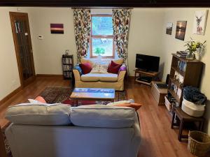 a living room with a couch and a tv at Midkinleith Farm Holiday Cottage in Edinburgh
