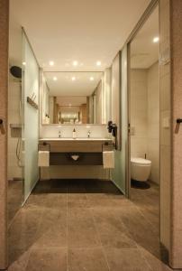 a bathroom with a tub and a sink and a toilet at Parkhotel Flora am Schluchsee in Schluchsee +52 photos