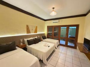 een hotelkamer met twee bedden en een televisie bij Recanto Verde Praia Hotel Juquehy in Juquei