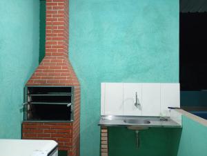 a kitchen with a sink and a brick oven at Chácara Mirante das Colinas in Atibaia