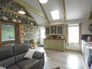 a living room with a couch and a stone wall at Sgubor Delyn Aberystwyth in Llanrhystyd +4 photos