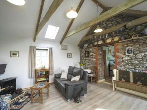a living room with a couch and a stone wall at Sgubor Delyn Aberystwyth in Llanrhystyd
