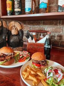 two plates of food with hamburgers and fries on a table at Jollyboys Backpackers and Camp in Livingstone