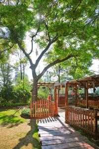 a wooden walkway under a tree in a park at Hotel Malas in Panchgani