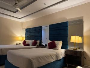 two beds in a hotel room with two lamps at Hotel Golden in Lahore +36 photos