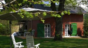 a red brick house with green doors and two white chairs at Bahnhof Droyßig - Übernachten im Denkmal in Droyßig