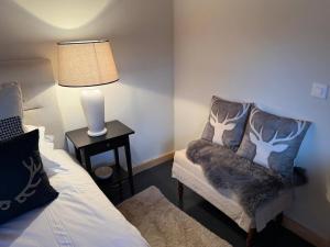 a room with a bed and a chair with a lamp at Little Chalet Piguet in Gryon