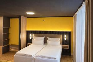 a bedroom with a white bed with a yellow wall at BEELiving Augsburg in Augsburg +3 photos