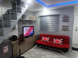 a living room with a red couch and a television at Charming 2-Bedroom Balanga Getaway with Ample Space in Balanga