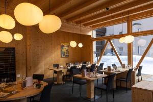 un ristorante con tavoli e sedie in legno e luci di Hotel Waldhaus Sils a Sils Maria