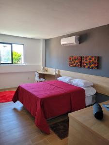 a hotel room with a bed with a red blanket at Carambola CoLiving in Olinda