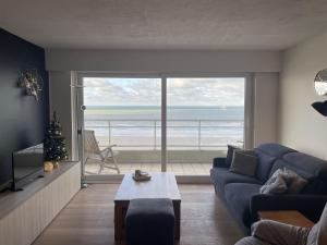 a living room with a blue couch and a view of the ocean at Golden Sun in Middelkerke