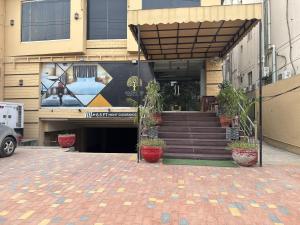 a building with stairs and potted plants in front of it at Hotel Golden in Lahore