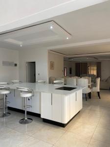 a kitchen with white cabinets and bar stools at PreshyPride Guest House in Victoria Falls