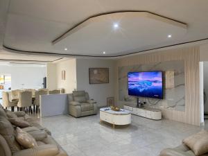a living room with a large tv on a wall at PreshyPride Guest House in Victoria Falls