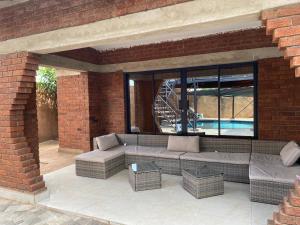 a brick patio with a couch and chairs and a pool at PreshyPride Guest House in Victoria Falls