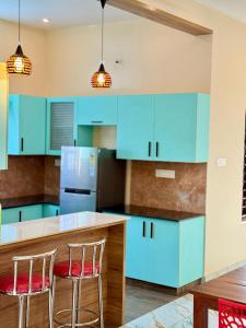 a kitchen with blue cabinets and two bar stools at Sunshine Holidays in Varkala +6 photos