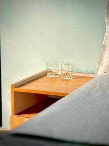 two glasses sitting on a table next to a bed at Sunshine Holidays in Varkala