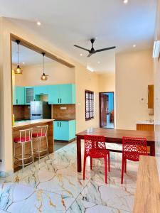 a kitchen with a wooden table and red chairs at Sunshine Holidays in Varkala