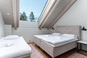 two beds in a room with a large window at Naava Chalet 401 Penthouse - Järvinäköala ilta-aurinkoon in Ähtäri