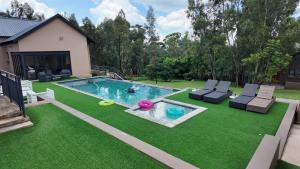a backyard with a swimming pool with chairs and a lawn at Villa 183 in Roodekrans