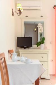 a white table with a tv on top of a dresser at Perla Hotel in Agios Prokopios