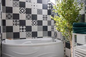 a bathroom with black and white tiles and a tub at Le Saint-Quentin - Studio avec Terrasse in Saint-Quentin
