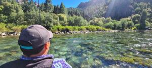 a man in a hat is looking at a river at Cabañas Betsaida in Lago Meliquina