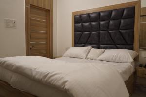 a bedroom with a large bed with a black headboard at Yatindra Ashraya in Etāwah