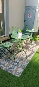 two green tables and chairs on a patio with grass at Orelli House - Bilocal Garden in Lissone