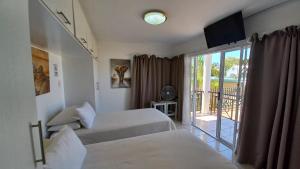 a bedroom with two beds and a balcony at Come Home in Oudtshoorn Self-Catering Units in Oudtshoorn