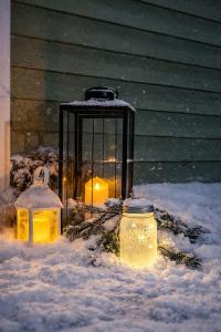 a candle in a cage in the snow at Lumi & Luonto - Entire 100 sqm 3-BR house with private wood fired sauna in Oulu