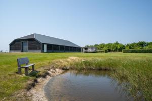a bench sitting next to a pond in front of a building at Johanneshoeve - de mooiste plek op Texel in Den Hoorn