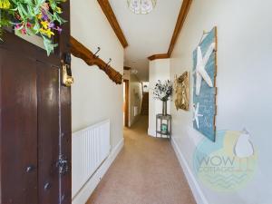 a hallway in a house with a door and flowers on the wall at Haslemere Cottage, Beer – Coastal Getaway Near the Beach in Beer