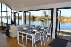 a dining room with a table and chairs with a view of the water at Riverside Lodge in Brundall