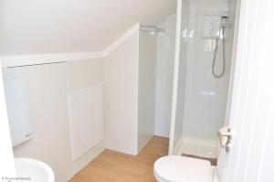 a white bathroom with a shower and a toilet at Riverside Lodge in Brundall