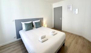a bedroom with a large white bed with two pillows at L'AUTHENTIQUE - Moderne - Central in Mont-de-Marsan