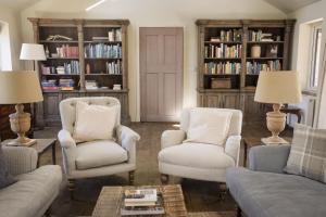 a living room with two chairs and a couch and bookcases at Relugas Mill in Forres