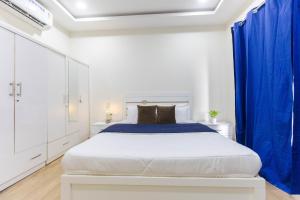 a white bedroom with a large bed with blue drapes at Indigo Studio by JadeCaps 1BHK New Town Kolkata in kolkata