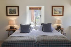 two beds in a room with two lamps and a window at Relugas Mill in Forres