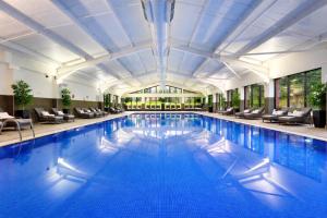 a large swimming pool with blue water in a building at Macdonald Hill Valley Hotel, Spa & Golf Resort in Whitchurch