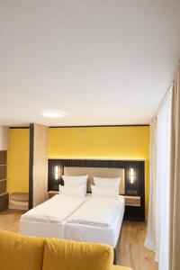 a bedroom with two beds and a yellow wall at BEELiving Augsburg in Augsburg