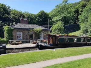 a boat is parked in front of a house at Lock Keepers Cottage at Salterhebble in Exley