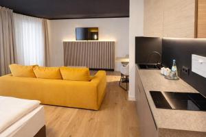 a living room with a yellow couch and a kitchen at BEELiving Augsburg in Augsburg