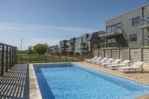 a swimming pool with lounge chairs next to a building at The Oak - Ekerum Öland in Borgholm