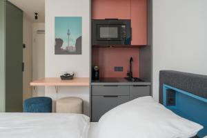 a small room with a bed and a kitchen with a microwave at Homaris Nolli Studios in Berlin