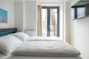 a white bed in a room with a window at Homaris Nolli Studios in Berlin