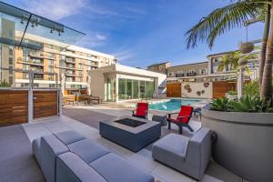 a patio with a couch and chairs and a pool at @ Marbella Lane - Luxury Beachside 2BR in Long Beach